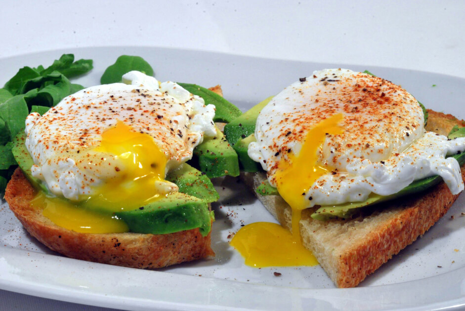 Avocado and poached eggs on toast, with runny yolk on top.