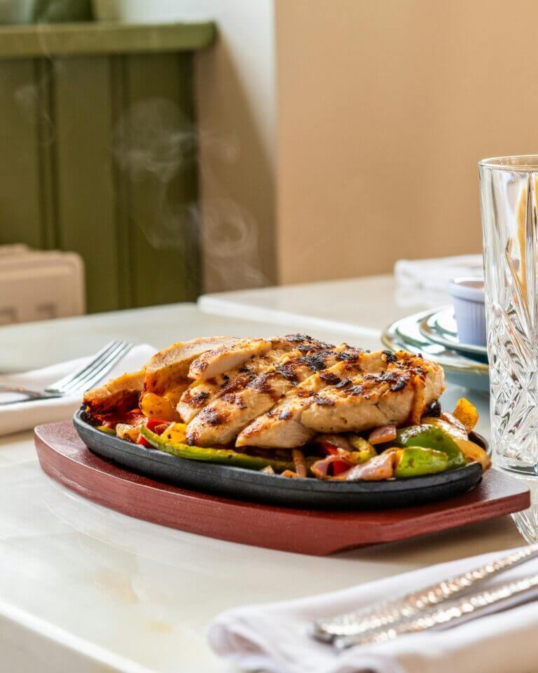 Delicious grilled chicken with colorful bell peppers served on a hot plate, perfect for lunch or dinner.