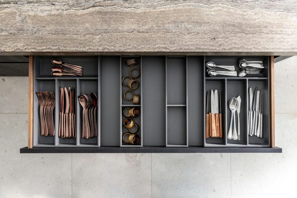 Dark gray drawer dividers with bronze-colored utensils in neat order.