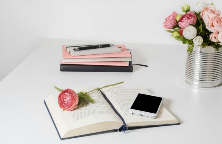 Book and pretty pink flowers on a white wooden table