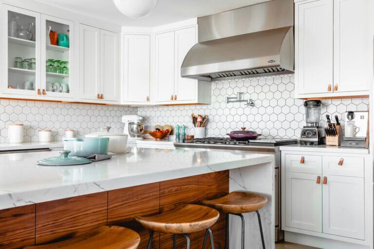 White kitchen with a teal dutch oven on the island.