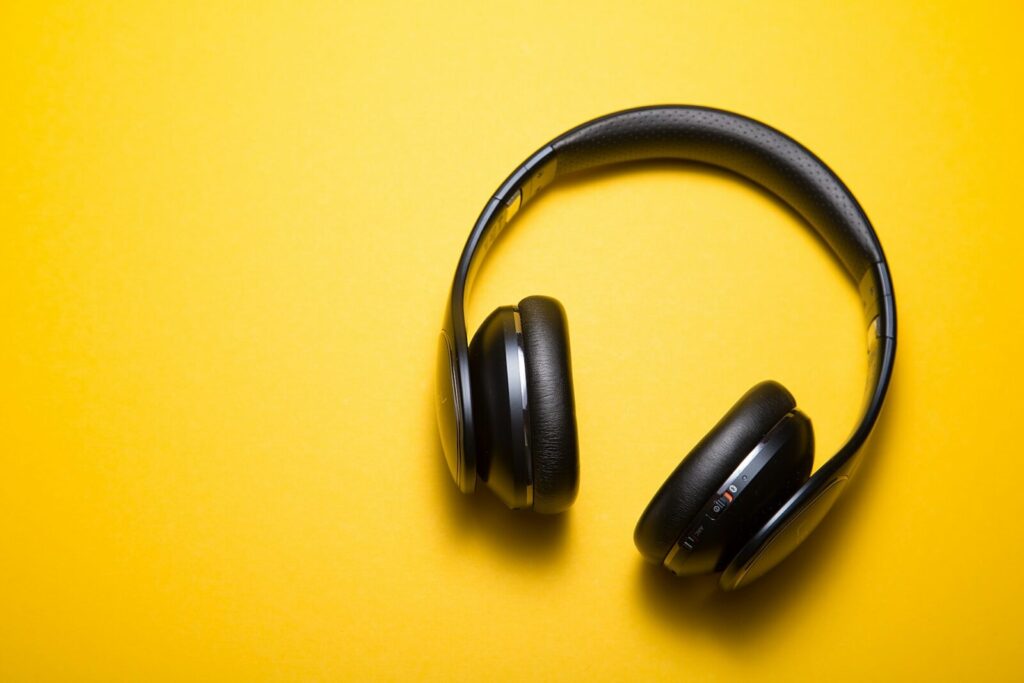 Black headphones against bright yellow background.