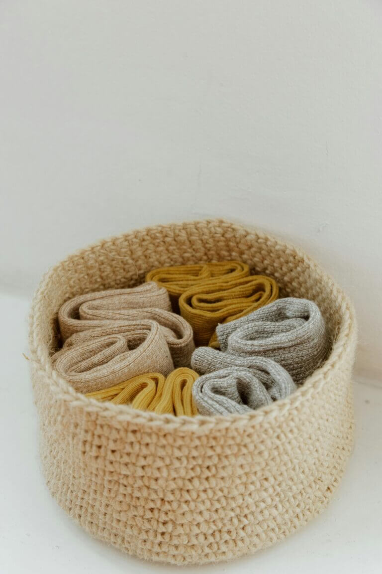 Six pairs of knitted socks in a basket.