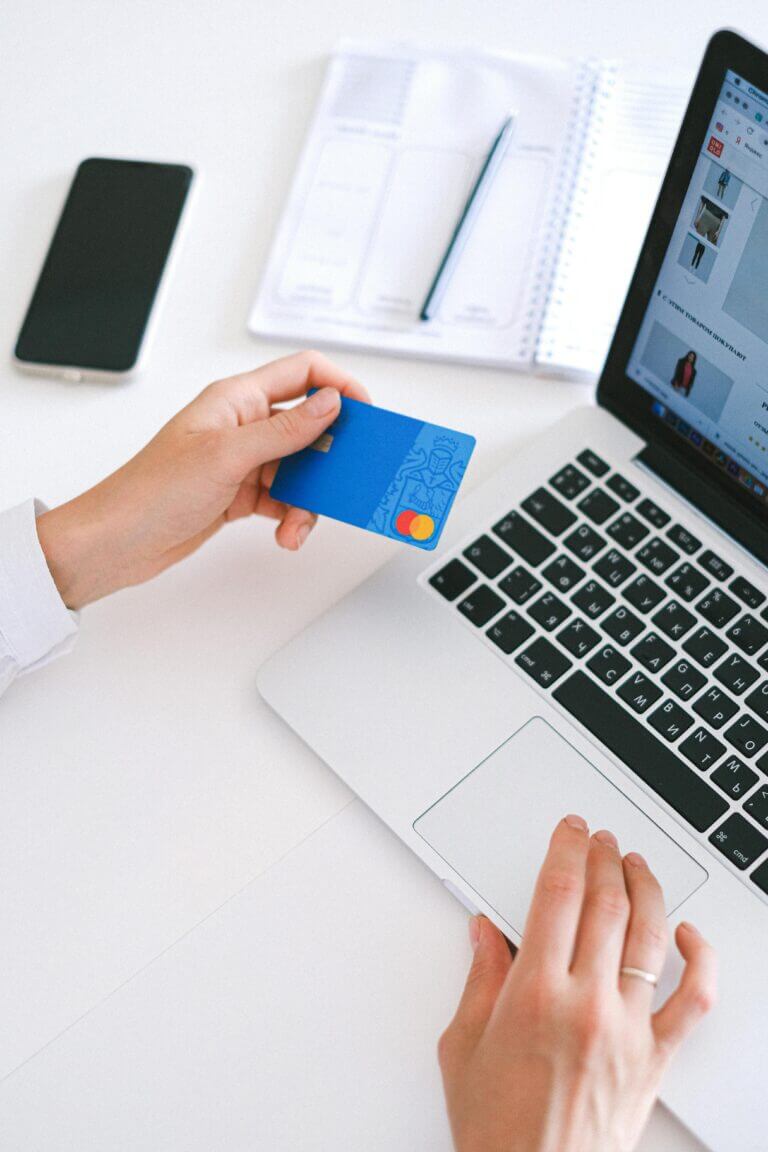 A woman holding a credit card while on a laptop.